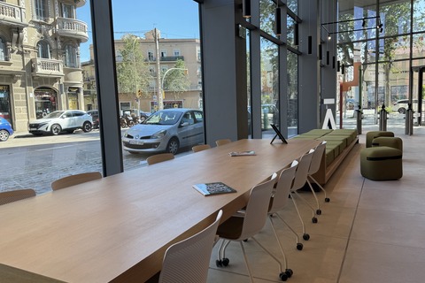 a long table with chairs and a couch in a room with windows