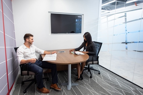 a man and a woman sitting at a table using a laptop