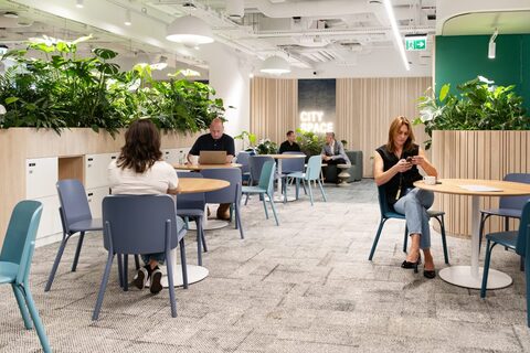 people sitting at tables in a room with plants