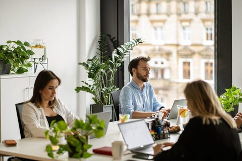 a group of people sitting at a table with laptops