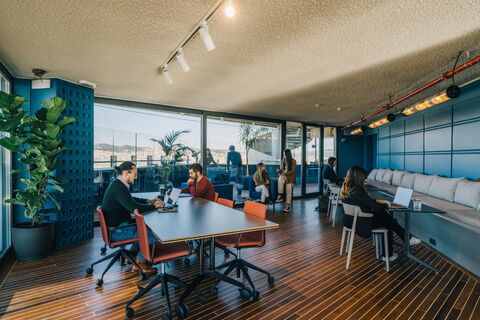 a group of people sitting at a table in a room with windows