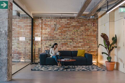 a woman sitting on a couch in a room with brick walls