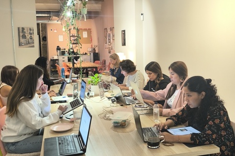 a group of people sitting at a table using a laptop computer