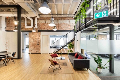 a room with a brick wall and a couch and chairs