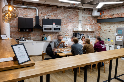 a group of people eating pizza in a room with brick walls