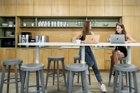two women sitting at a table with laptops