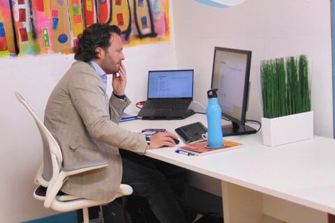a man sitting at a desk with a laptop and a bottle of water