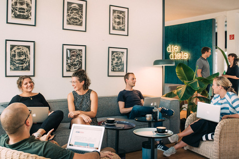 a group of people sitting at a table using a laptop