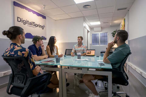 a group of people sitting at a table using a laptop