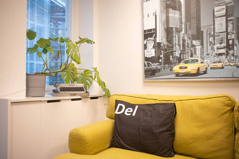a yellow couch with a black pillow and a picture on the wall