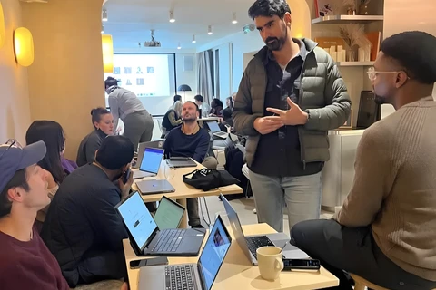 a group of people sitting around a table with laptops