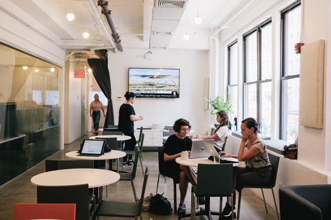 a group of people sitting at a table using a laptop