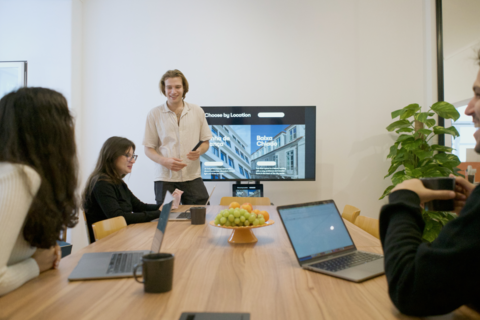 a group of people sitting at a table using a laptop computer