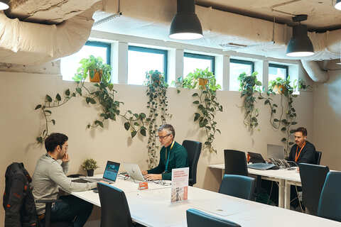 a group of men sitting at a table with laptops