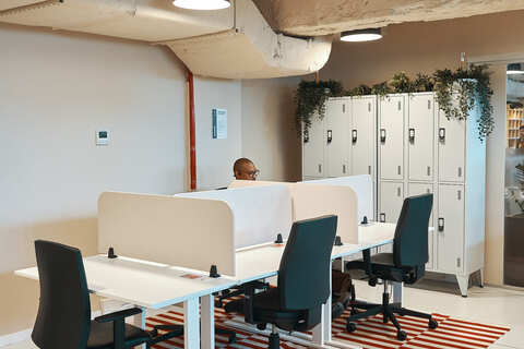 a man sitting at a desk in a room with white tables and chairs