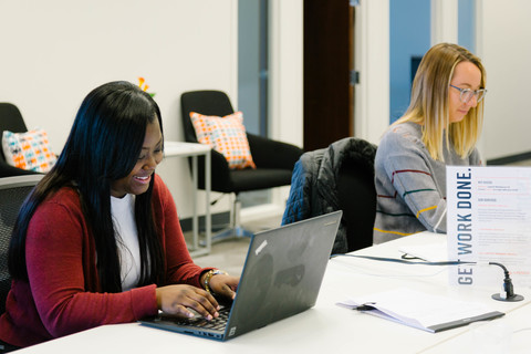 a woman sitting at a table using a laptop computer