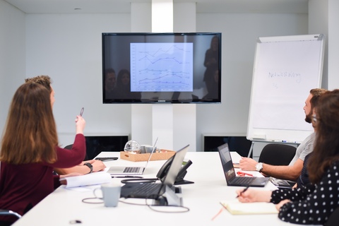 a group of people sitting at a table using a laptop
