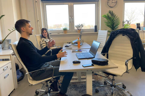 a group of people sitting at a table using a laptop computer