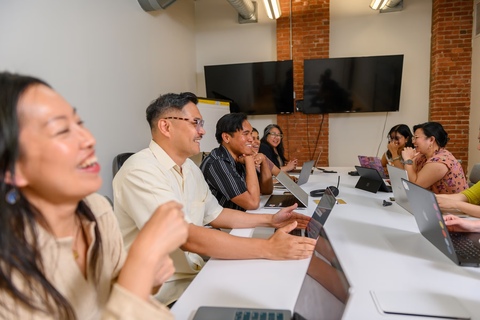 a group of people sitting at a table with a laptop
