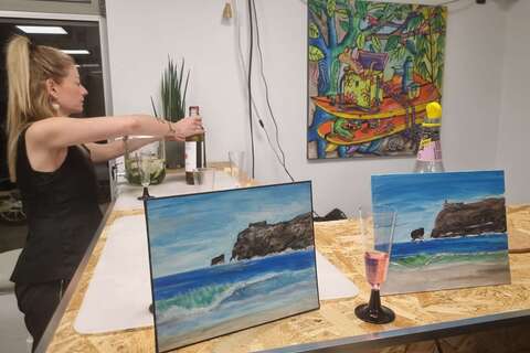 a woman sitting at a table with paintings on it