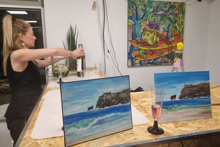 a woman sitting at a table with paintings on it