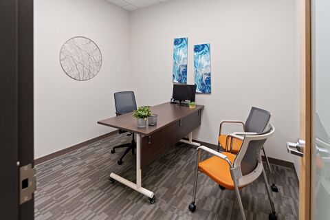 a desk with chairs and a computer
