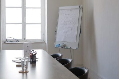 a table with chairs in front of a white board
