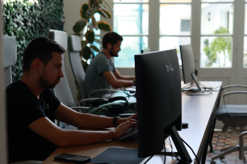 a group of men sitting at a desk with computers