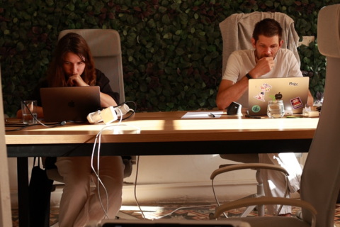 a man and woman sitting at a table with laptops