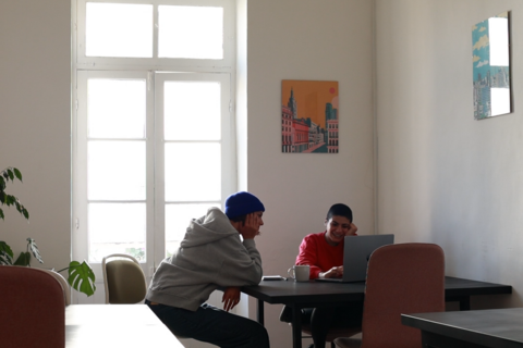 two people sitting at a table with a laptop