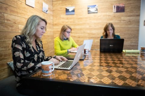 a group of people sitting at a table using a laptop