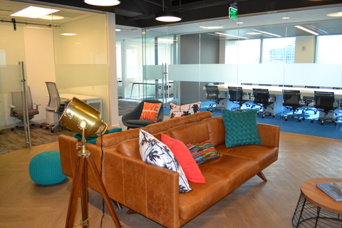 a brown leather couch with pillows in a room with a lamp
