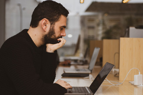 a man sitting at a table using a laptop computer