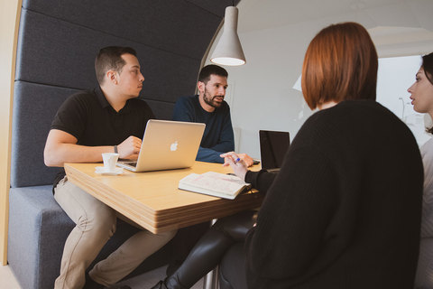 a group of people sitting at a table with a laptop
