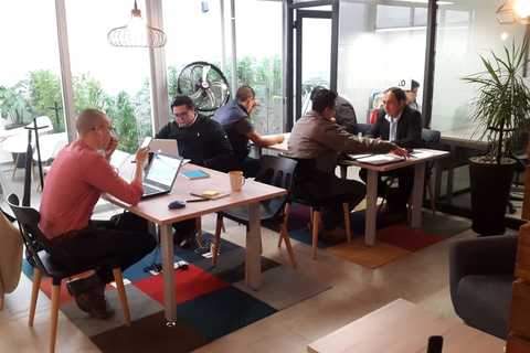 a group of people sitting at a table using a laptop computer