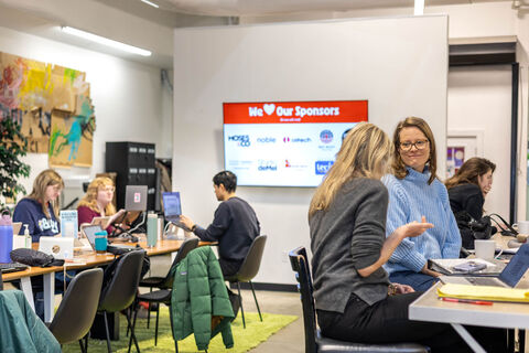 a group of people sitting at a table using a laptop