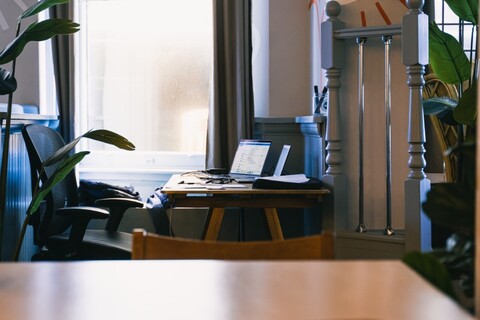 a desk with a laptop in front of a window