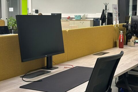 a desk with a computer in an office chair