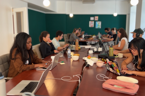 a group of people sitting at tables with laptops