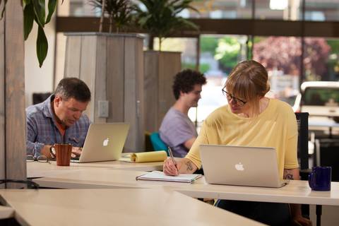 a group of people sitting at a table using a laptop computer