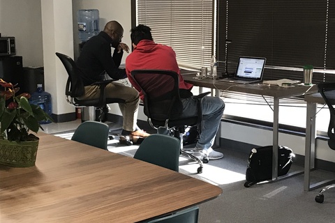 a group of people sitting at a desk in front of a window