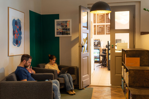 a man and woman sitting in chairs in a room with a door open